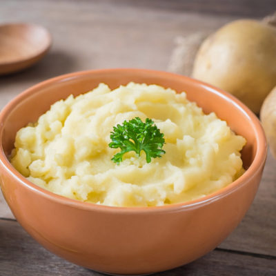 Bowl of creamy mashed potatoes with a parsley garnish.