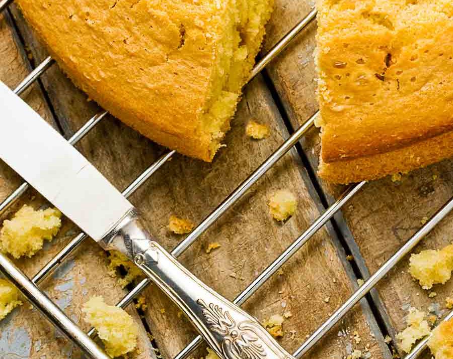 Angel food cake on a baking sheet, with a piece cut out and a knife nearby.