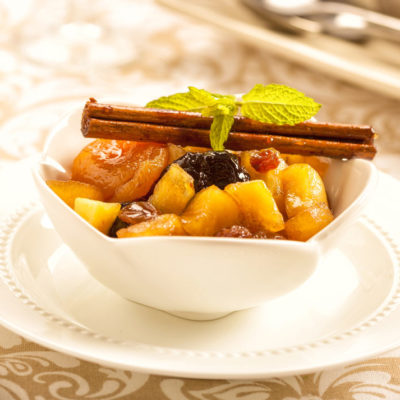 Hot Fruit Compote, a bowl of cooked fruit topped with a cinnamon stick