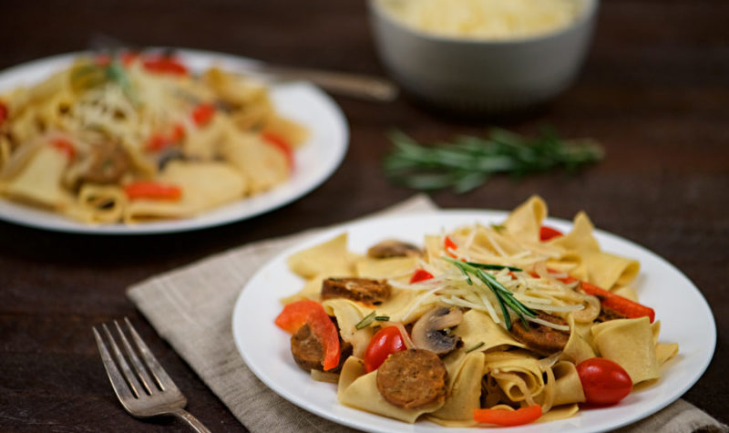 Sausage and Pappardelle Pasta on a white plate.