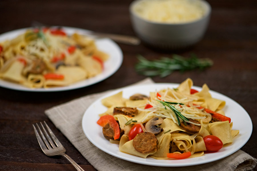 Sausage and Pappardelle Pasta on a white plate.