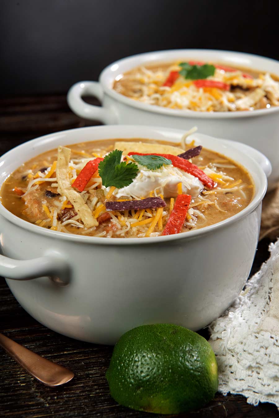 A bowl of chicken enchilada soup topped with cheese and tortilla strips.