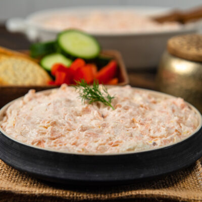 A bowl of salmon dip with a sprig of dill on top.