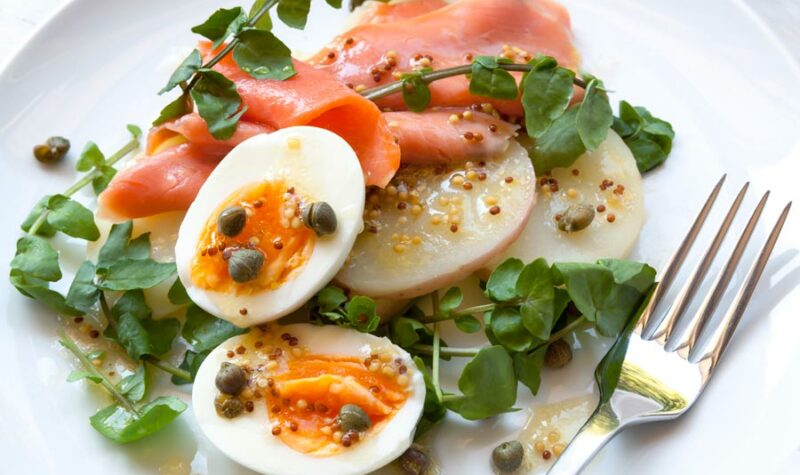 Salmon Salad with hard boiled egg and capers on a bed of lettuce.