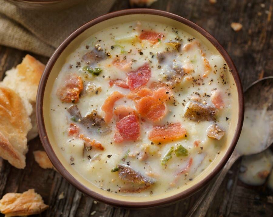 Bacon Potato and Cabbage Soup in a brown bowl with bread on the side.