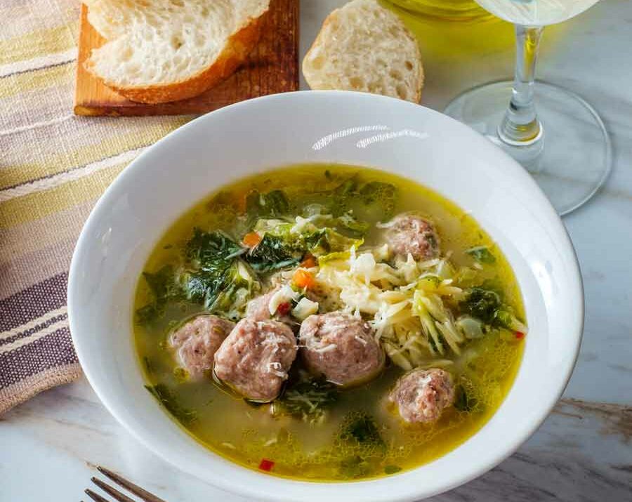 Italian wedding soup with meatballs in a white bowl.