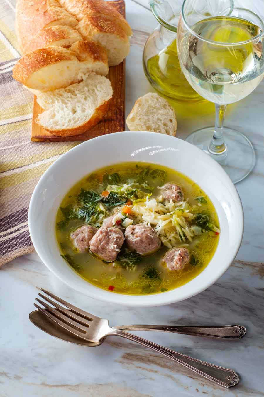 Italian wedding soup with meatballs in a white bowl.