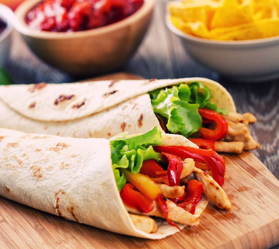 Chicken Fajitas in a tortilla with lettuce and tomato and peppers.