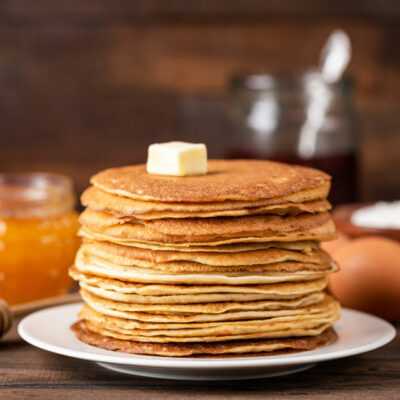 Buckwheat pancakes on a white plate with honey in the background