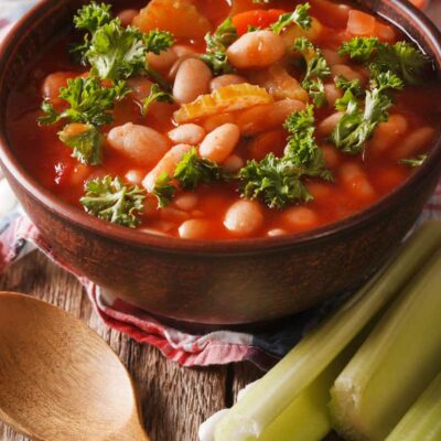 Minestrone soup in a bowl with a wooden spoon