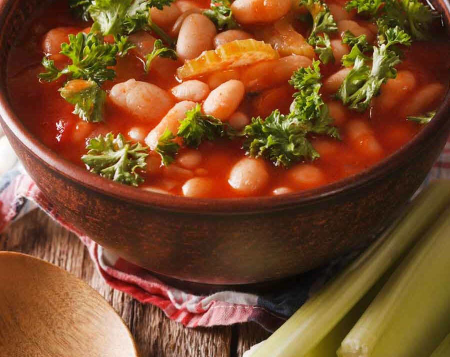 Minestrone soup in a bowl with a wooden spoon