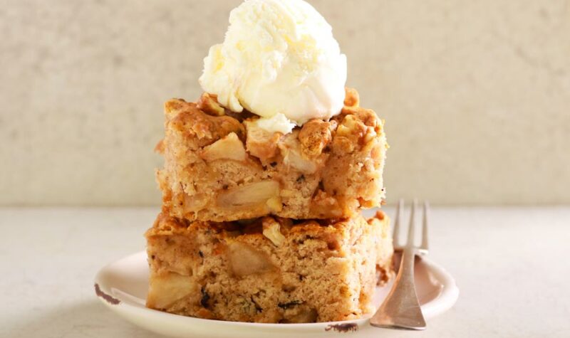 Apple cake on a plate topped with ice cream