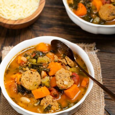 A bowl of minestrone soup with turkey sausage, carrots and sweet potatoes.