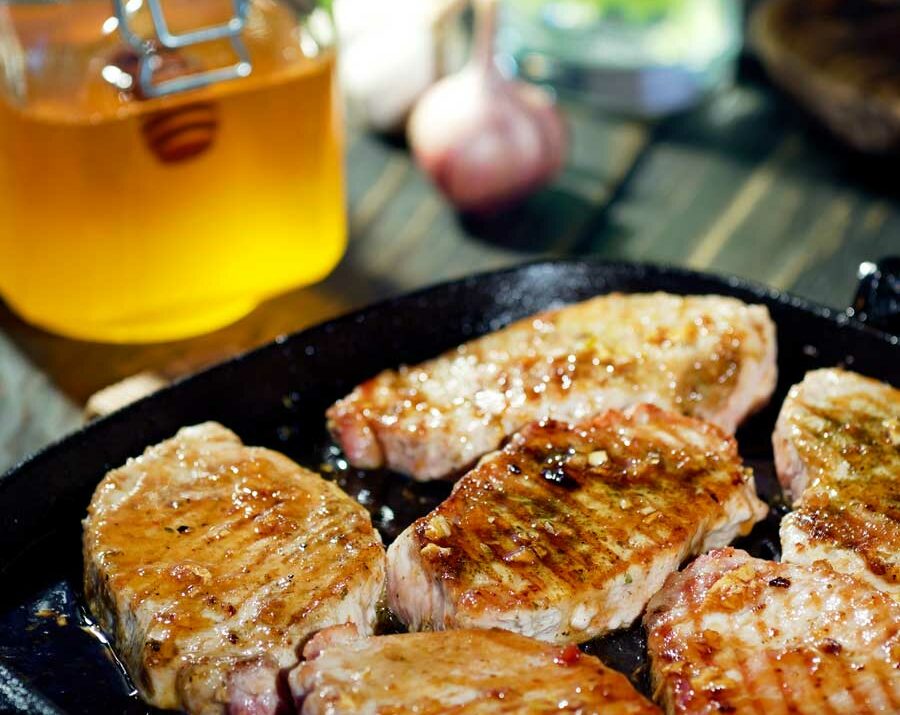 Grilled Pork Chops with honey in the background.