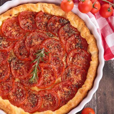 Tomato Tart in a white baking dish with tomatoes on the side.
