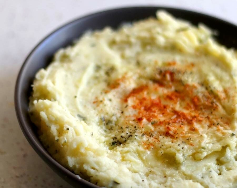 A bowl of mashed potatoes with paprika sprinkled on top