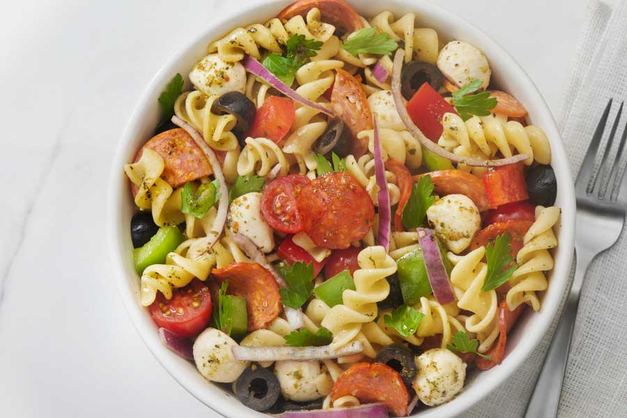 pasta salad in a bowl with salami and veggies
