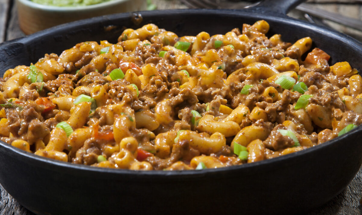 A skillet filled with taco pasta salad with corn chips on the side