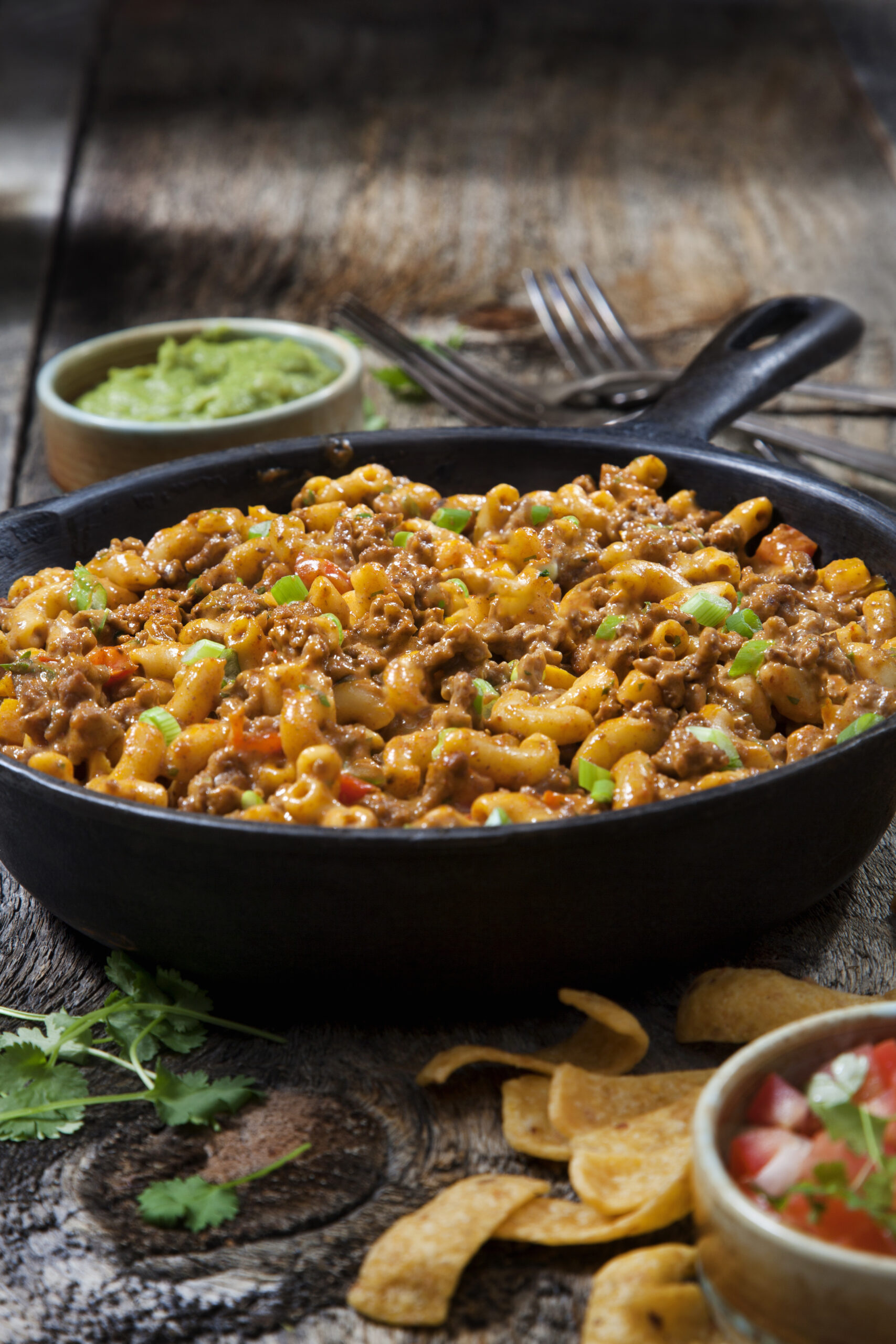 A skillet filled with taco pasta salad with corn chips on the side