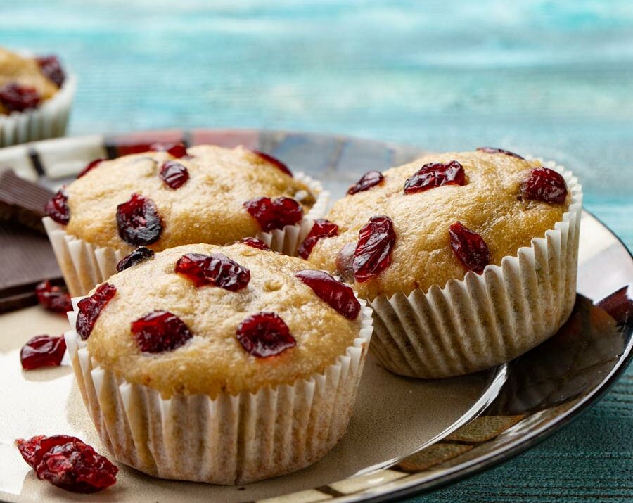 Cherry Oat muffins on a plate with cherries on the side.