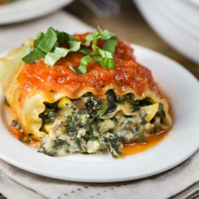 A lasagna roll filled with spinach on a white plate