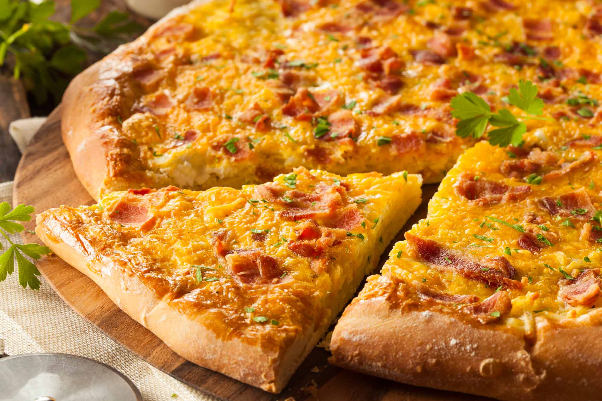 A bacon breakfast pizza on a cutting board