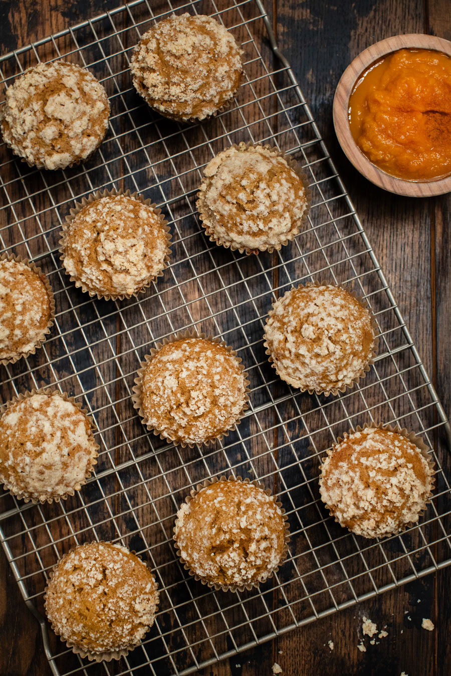 Streusel pumpkin muffins on a baking sheet with pumpkin on the side.
