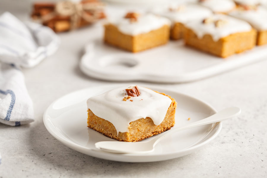 A pumpkin bar and a white plate with frosting and a spoon