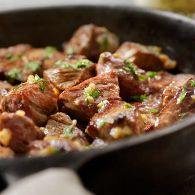Sirloin tips (cubed steak) on a cast iron pan with garlic