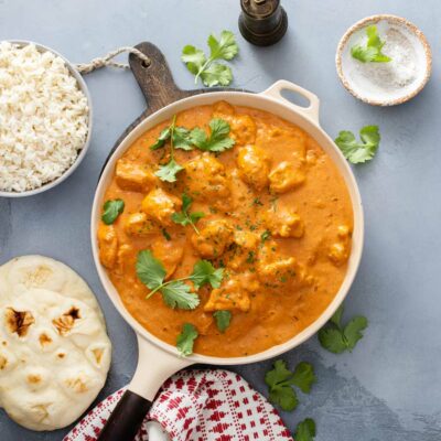 Butter chicken in a skillet with rice on the side