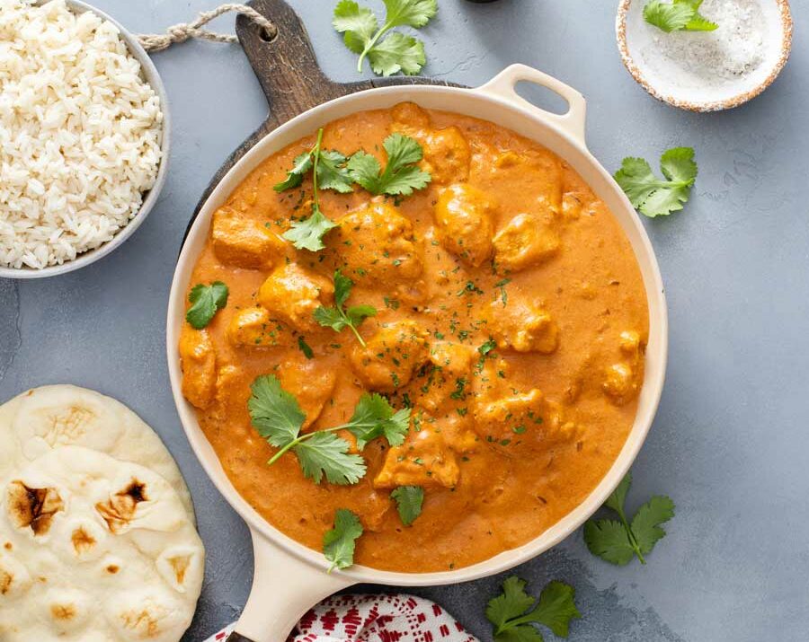 Butter chicken in a skillet with rice on the side