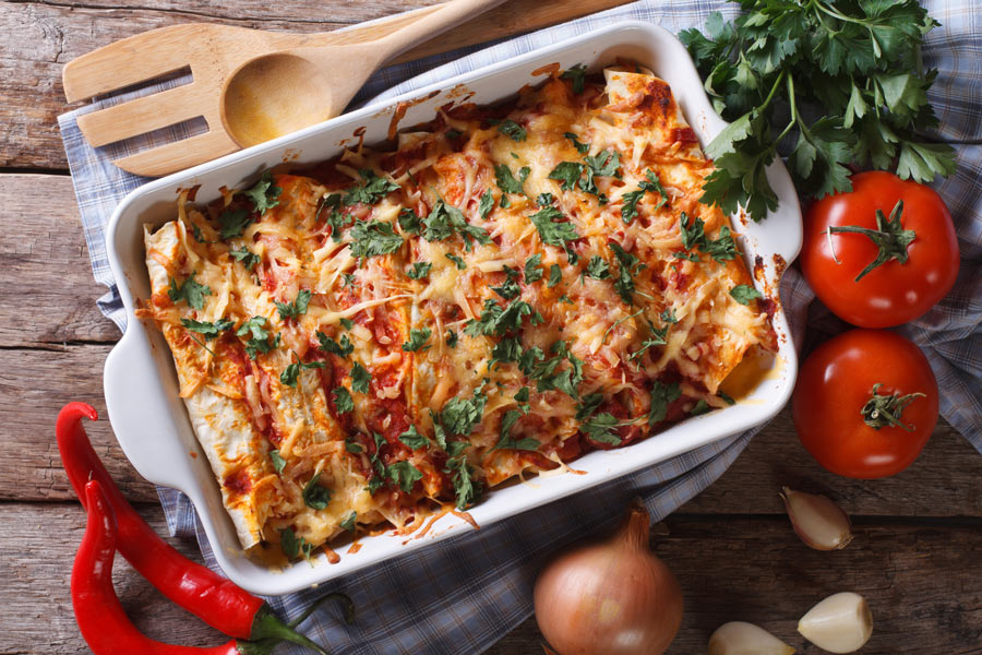 Veggie Enchiladas in a baking pan covered in cheese