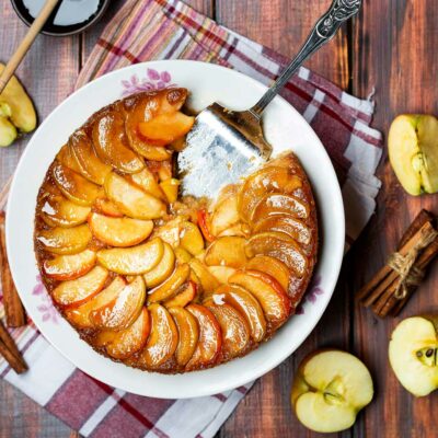 Caramel Apple Cake in a white dish with apples on the side.