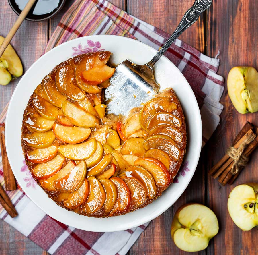 Caramel Apple Cake in a white dish with apples on the side.