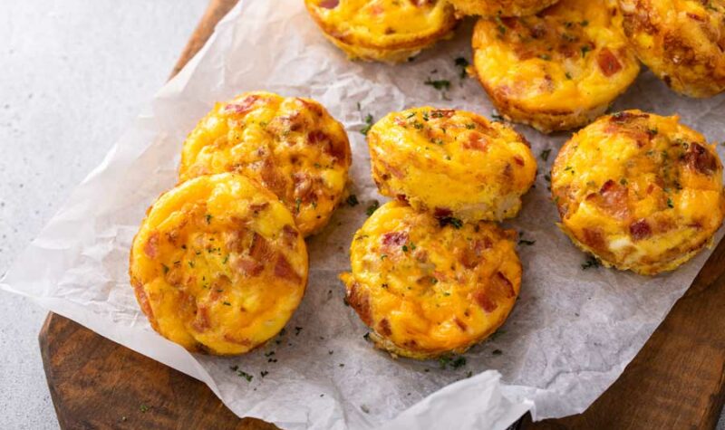 Bacon and cheddar cheese egg bites on parchment paper