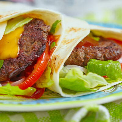 Tortillas filled with burger, lettuce, tomato and cheese.