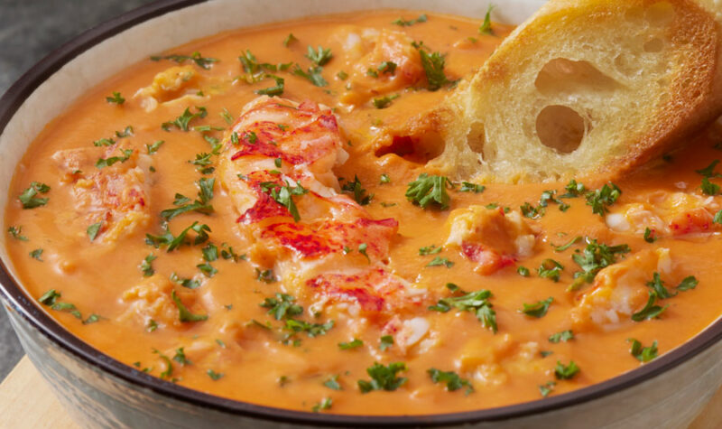 Lobster Bisque soup in a white bowl with bread