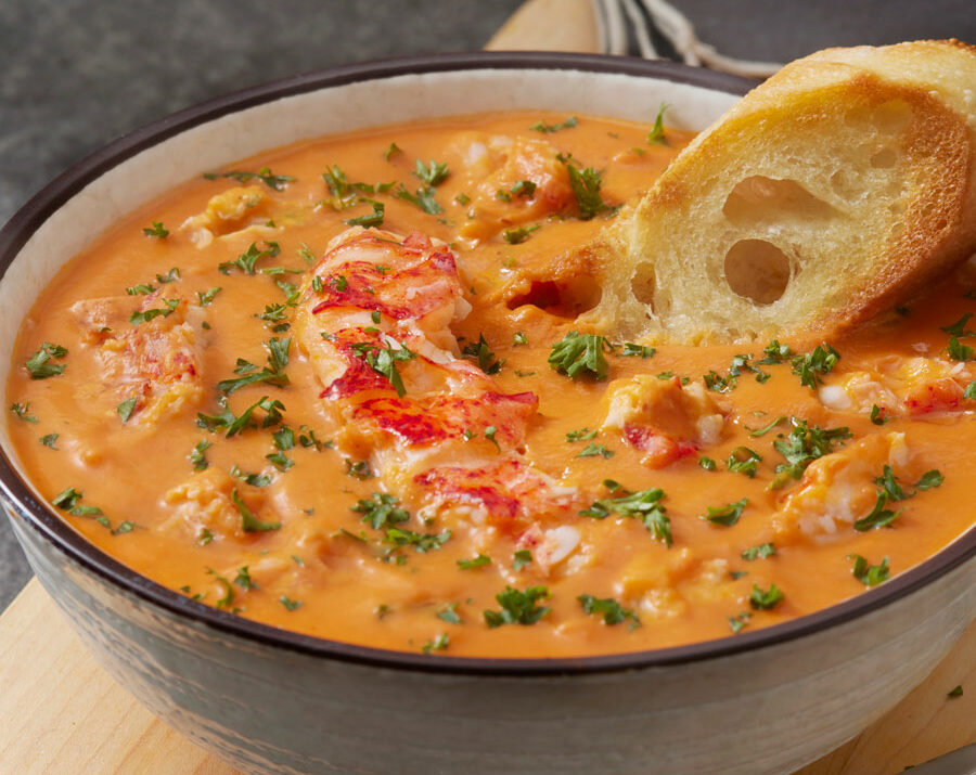 Lobster Bisque soup in a white bowl with bread