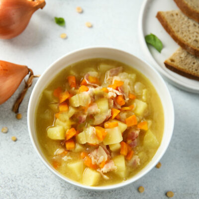 Potato soup in a white bowl with carrots and celery