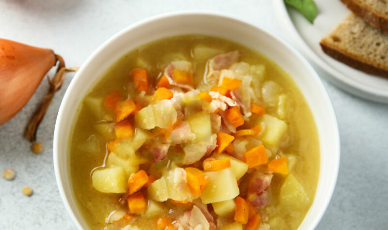 Potato soup in a white bowl with carrots and celery