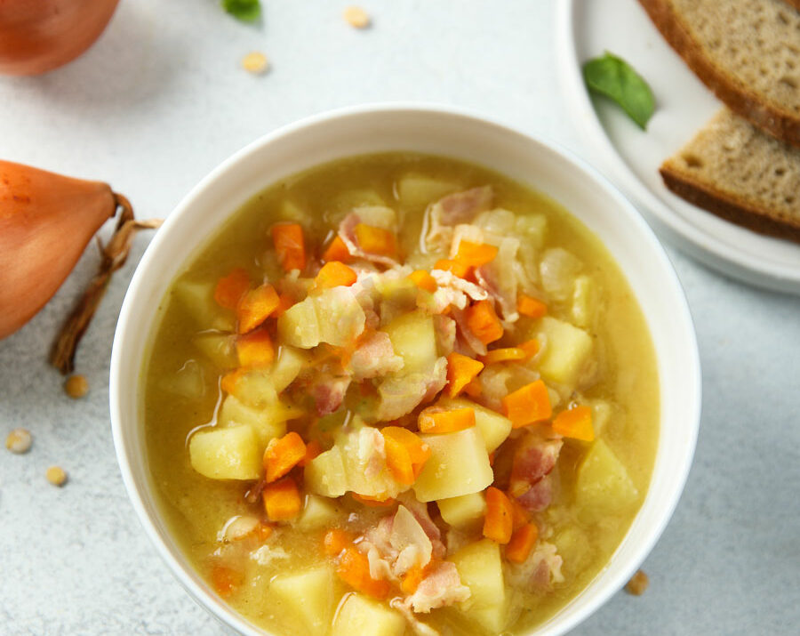 Potato soup in a white bowl with carrots and celery