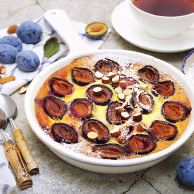 Red plums clafoutis (flan), icing sugar dressing, french cuisine - stock photo
