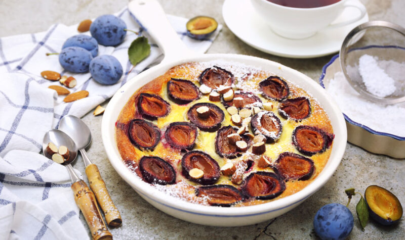 Red plums clafoutis (flan), icing sugar dressing, french cuisine - stock photo