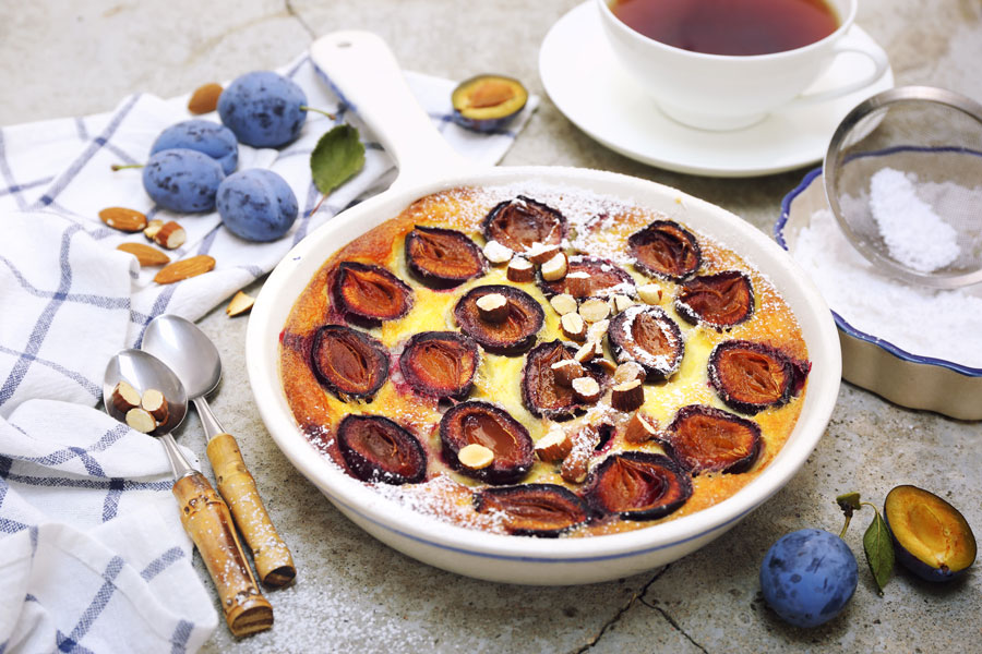 Red plums clafoutis (flan), icing sugar dressing, french cuisine - stock photo