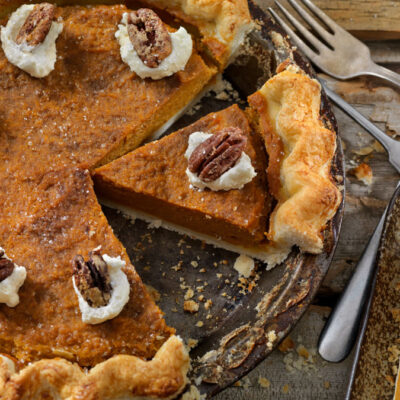 A pumpkin pie topped with whipped cream and a pecan
