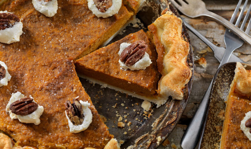 A pumpkin pie topped with whipped cream and a pecan