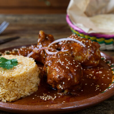 Chicken with a chocolate mole sauce and rice on the side.