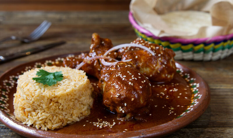 Chicken with a chocolate mole sauce and rice on the side.