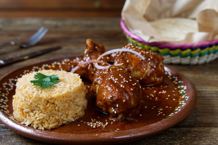 Chicken with a chocolate mole sauce and rice on the side.