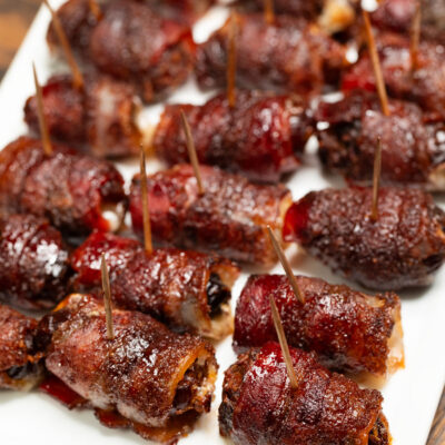 Bacon wrapped dates on a white plate